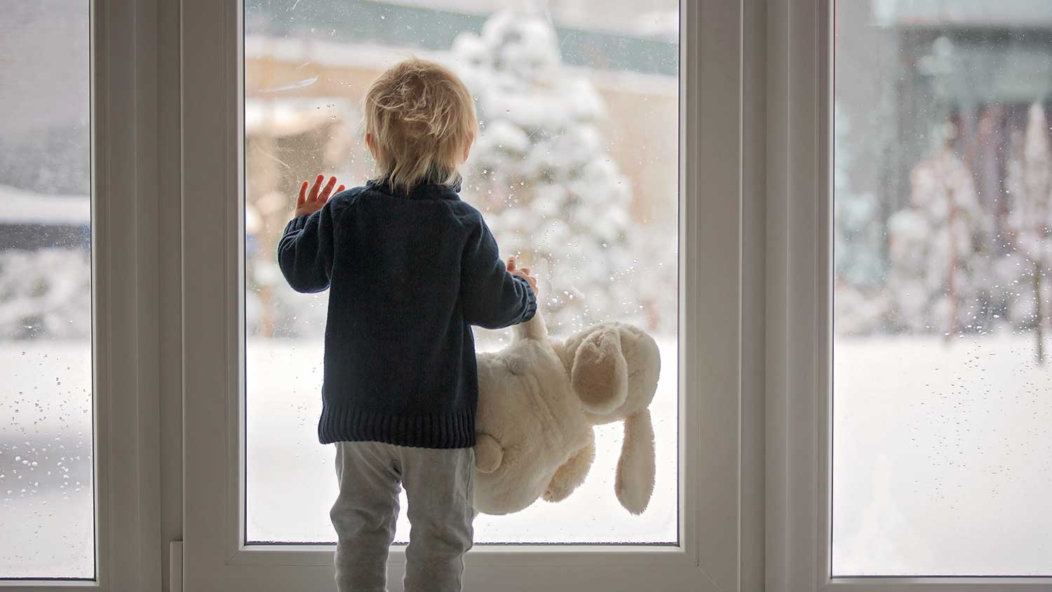 Kid looking out window at snow