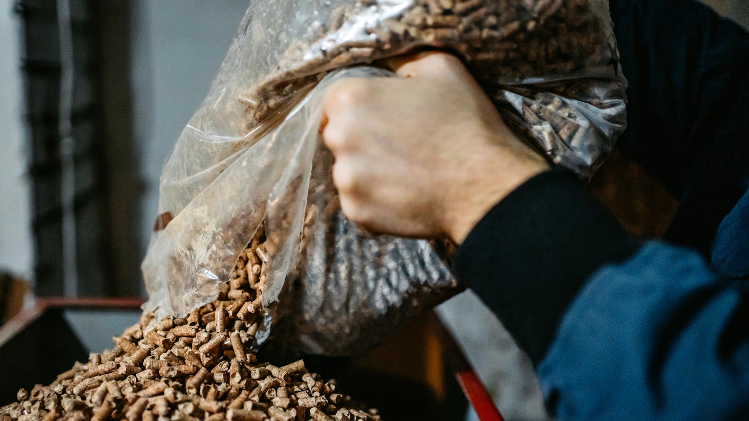 Close-up of a man pouring pellet in a stove