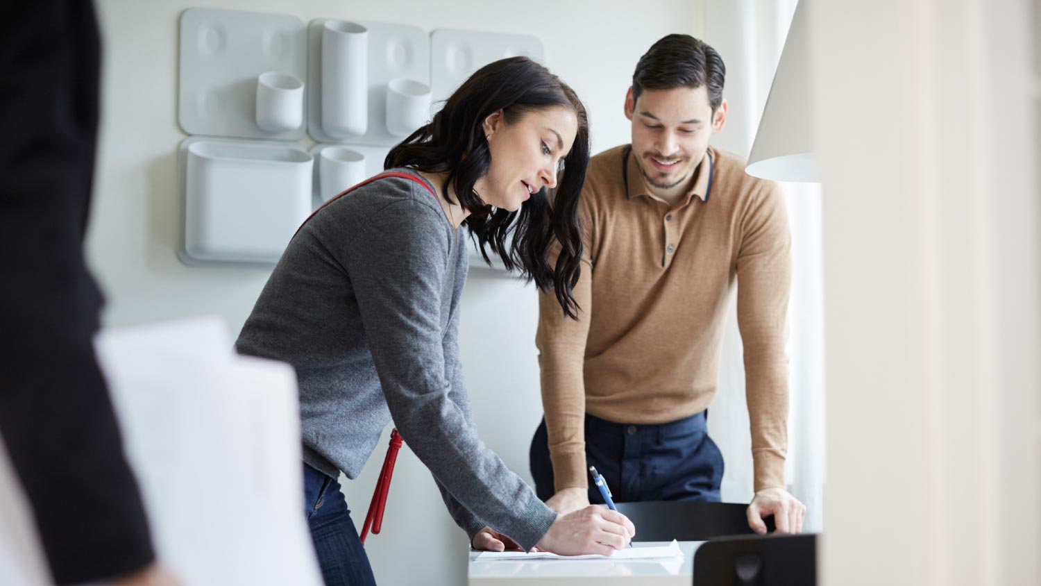 Man looking at woman signing papers of new house