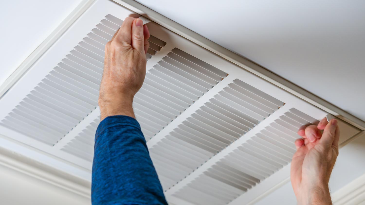 Man opening ceiling air vent