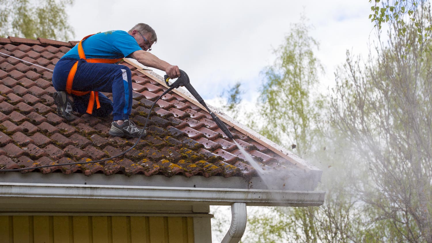 A man washing the roof with a high pressure washer