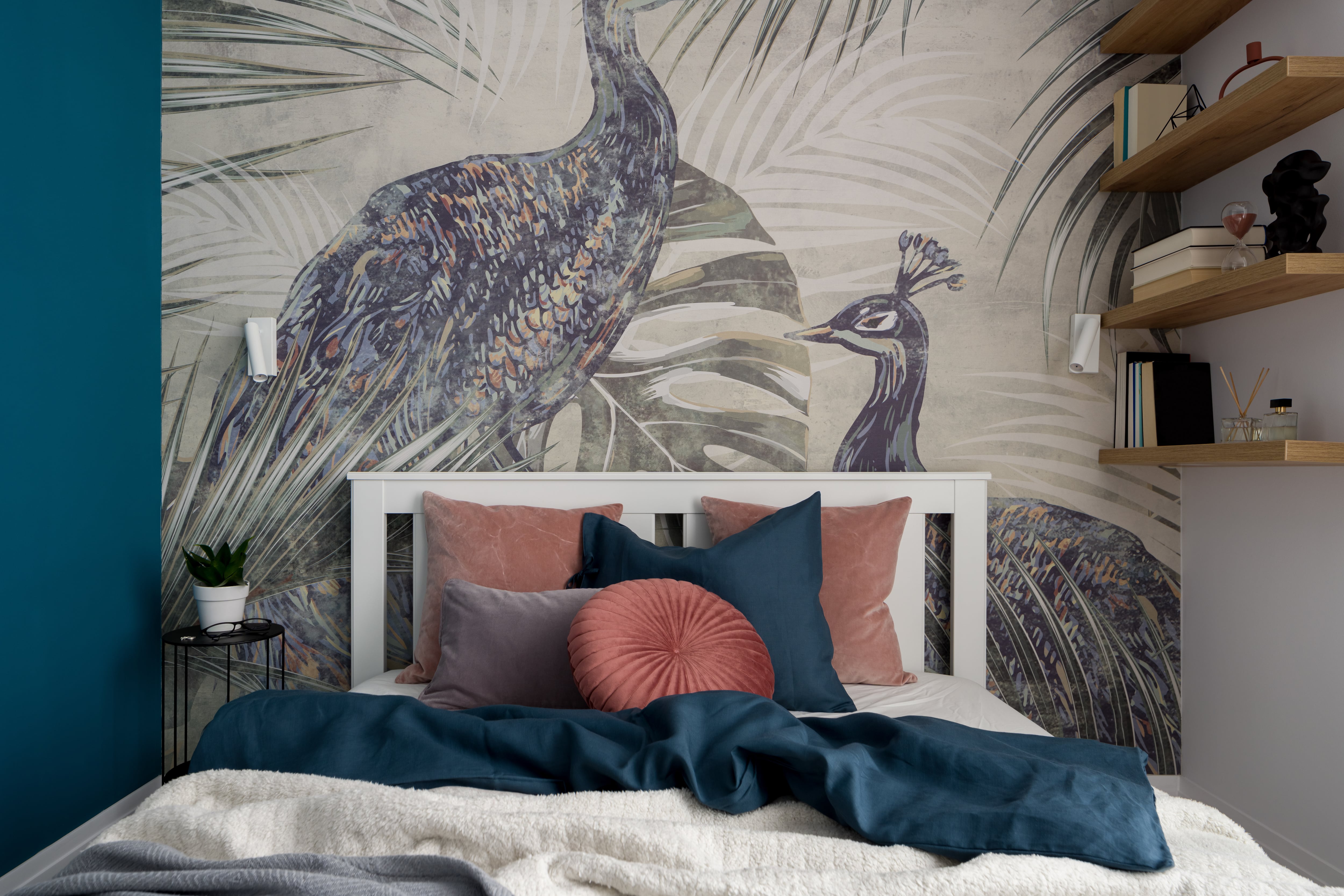 Bedroom with a bed pushed up against an accent wall of peacocks