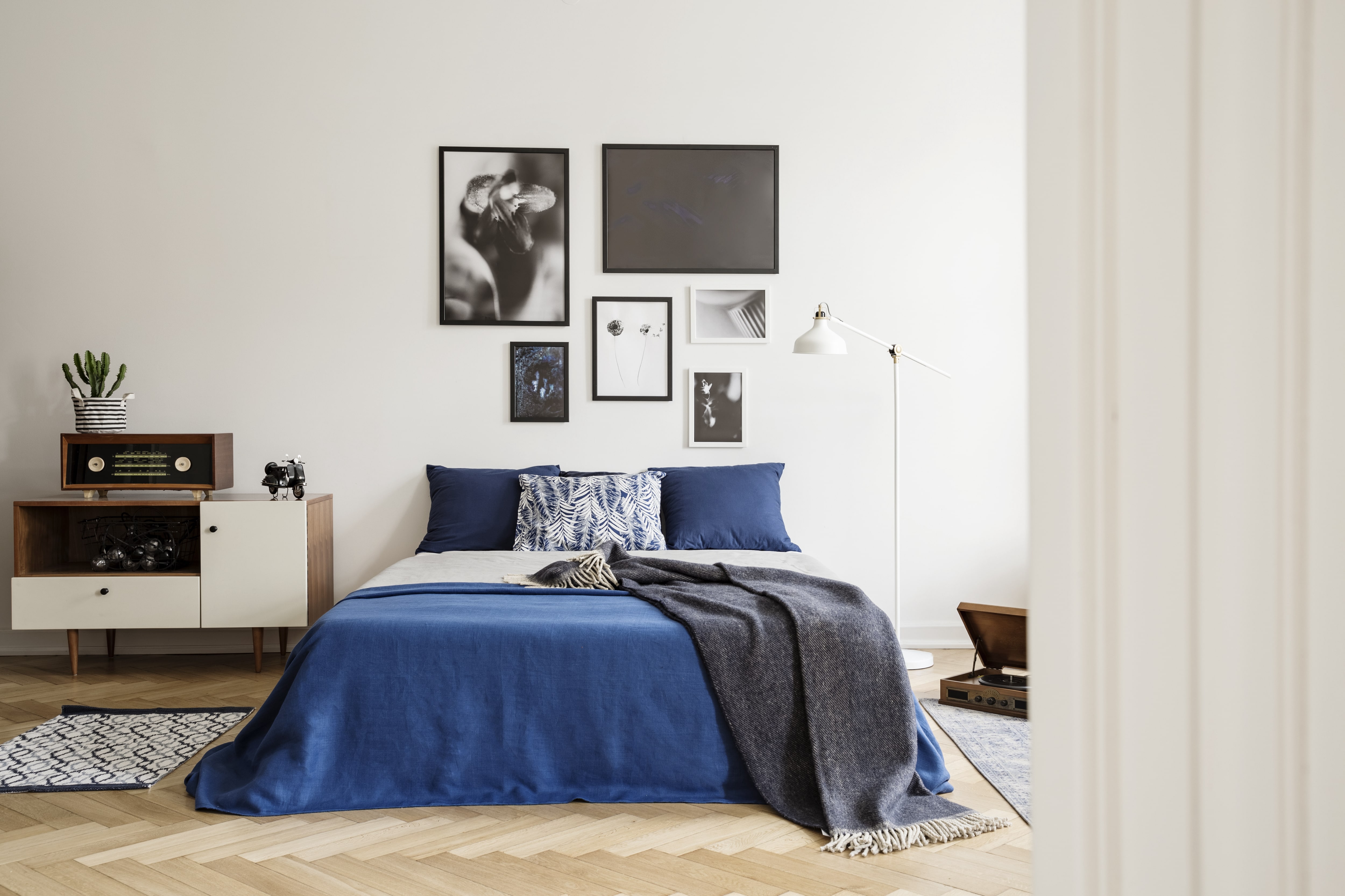 Bedroom with a bed and blue bedspread and gallery wall