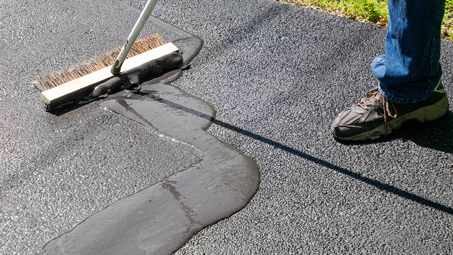 Person resealing asphalt driveway