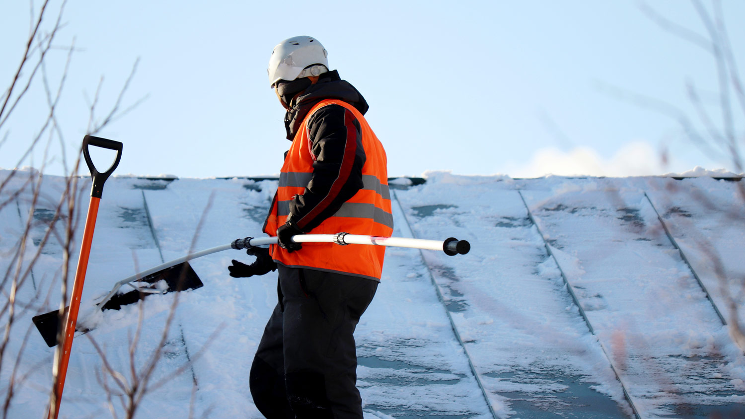 Professional removing snow on roof of home