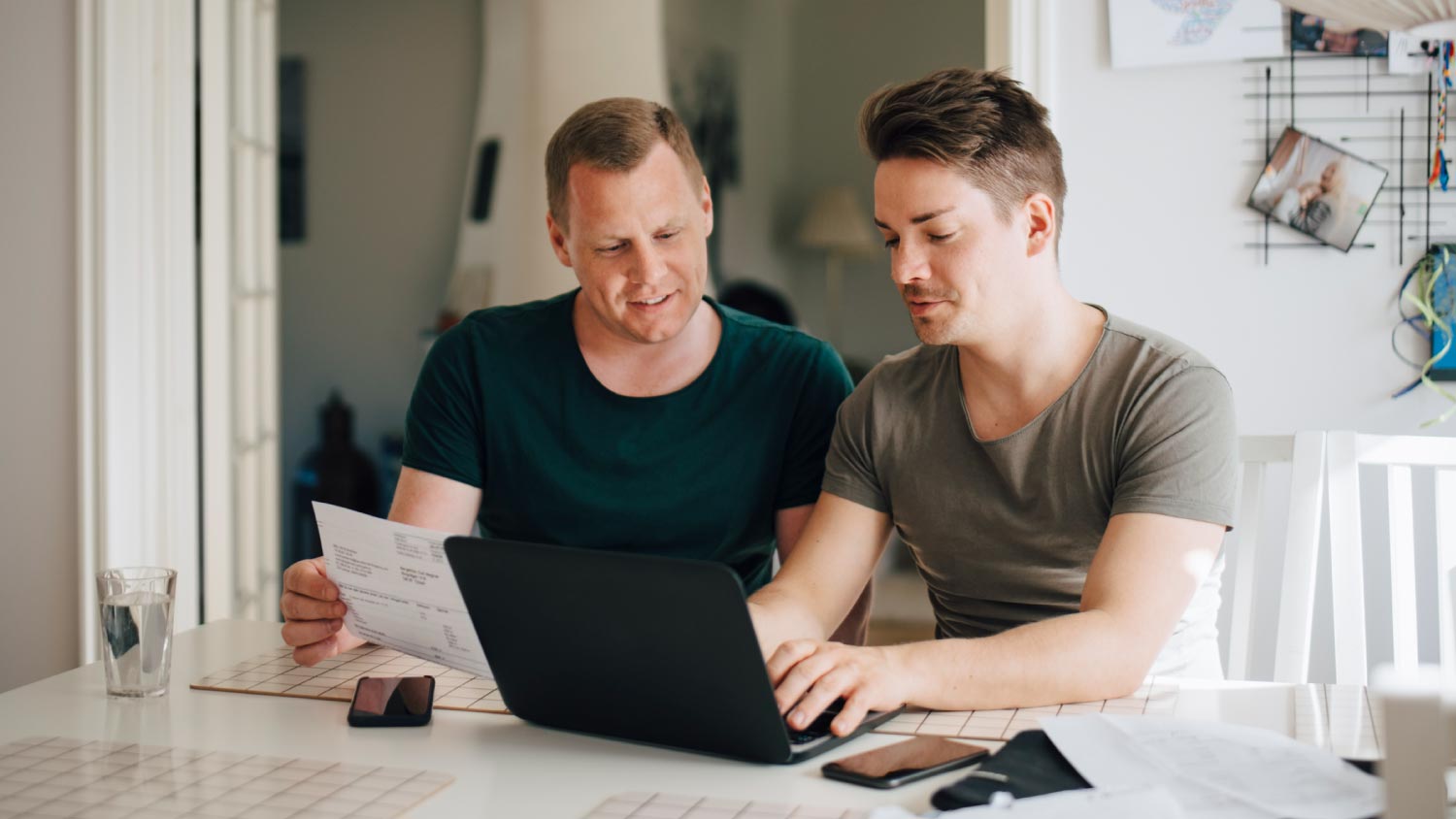 Smiling male couple paying bills