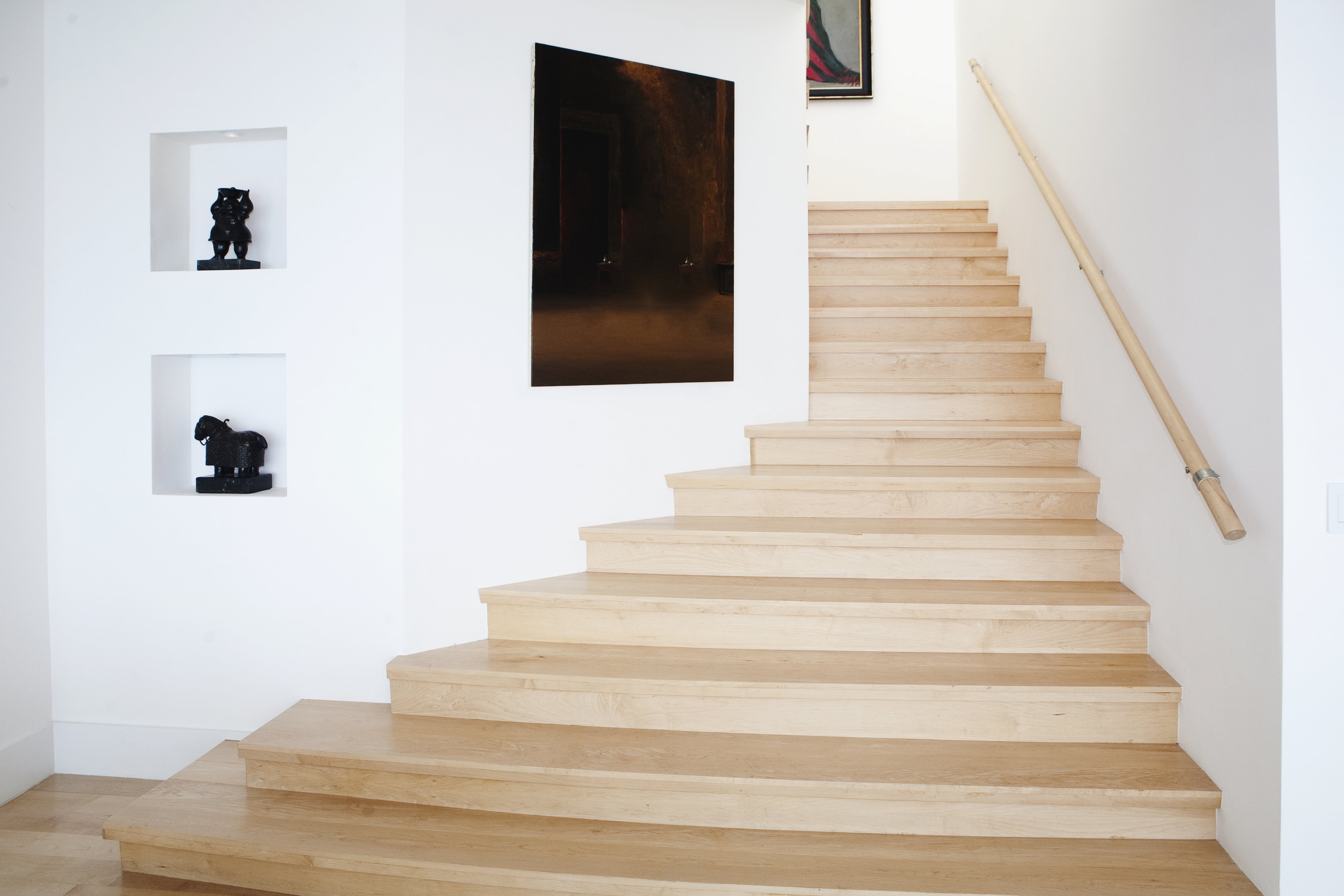 A modern interior staircase with a large piece of framed artwork on the wall