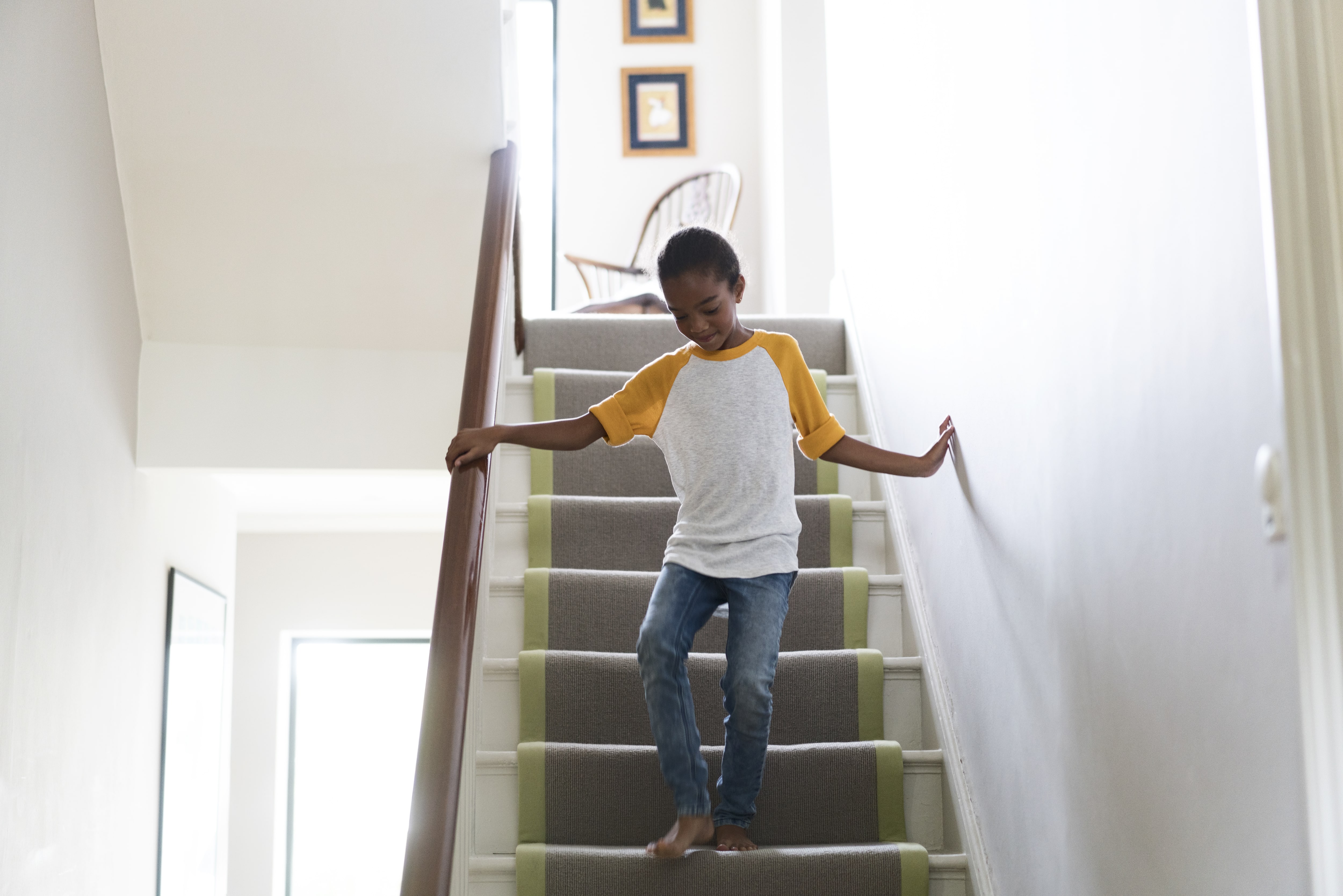 A young girl going down an interior staircase with a no-slip runner