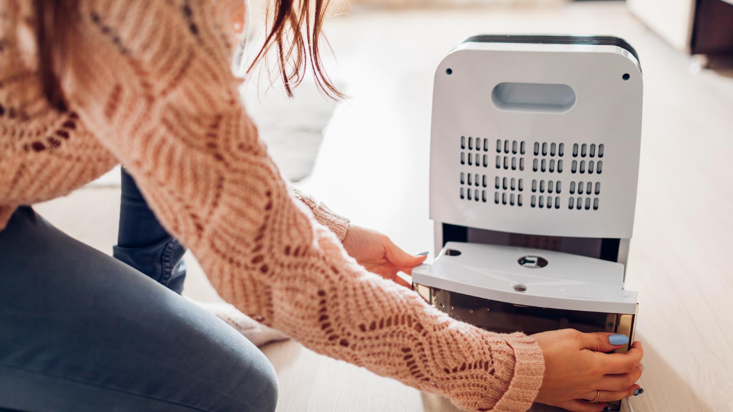 Woman changing water container of dehumidifier