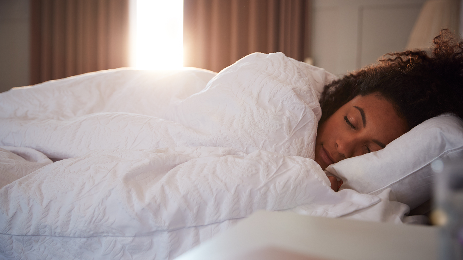 Woman sleeping in bed with white comforter