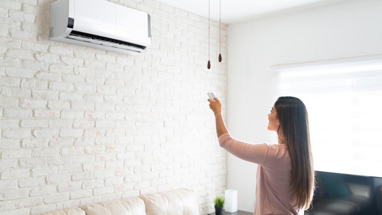 woman adjusting temperature with remote 