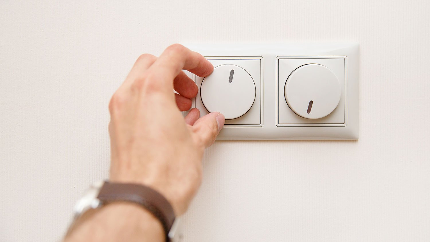 Closeup of a hand adjusting dimmer switch