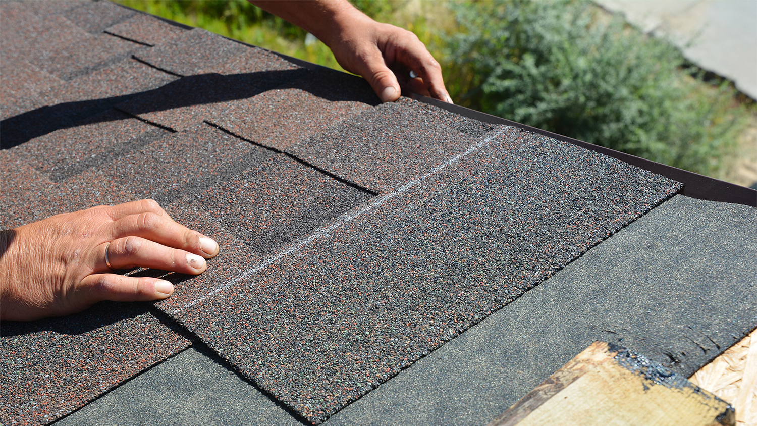 man installing asphalt shingles panels to roof