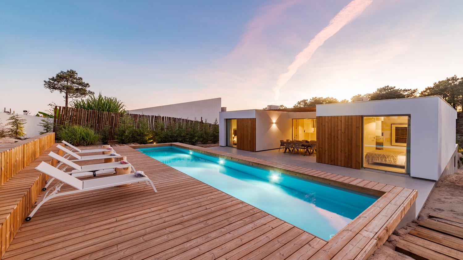 A house’s backyard with a pool and a wooden deck