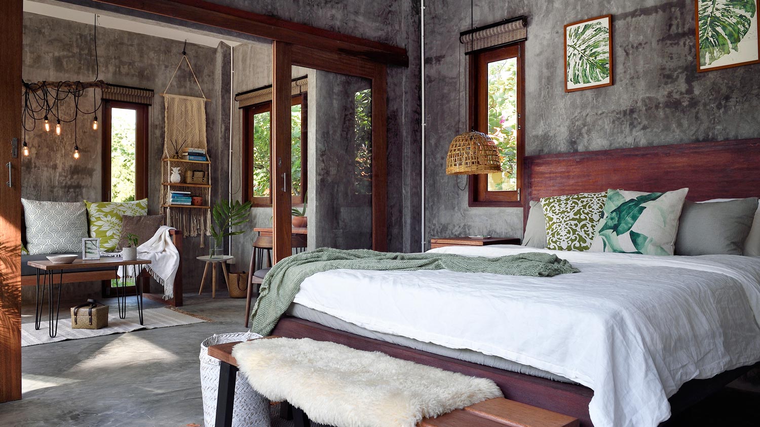 A bedroom with concrete floor and a door leading to a living room