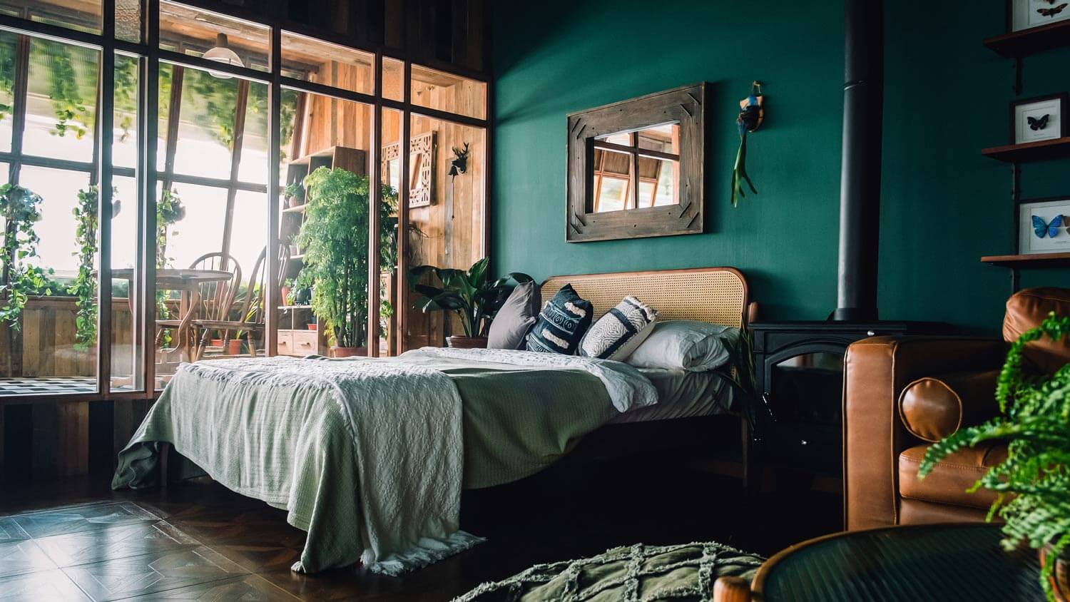 A bedroom with a rattan bed and dark green painted wall