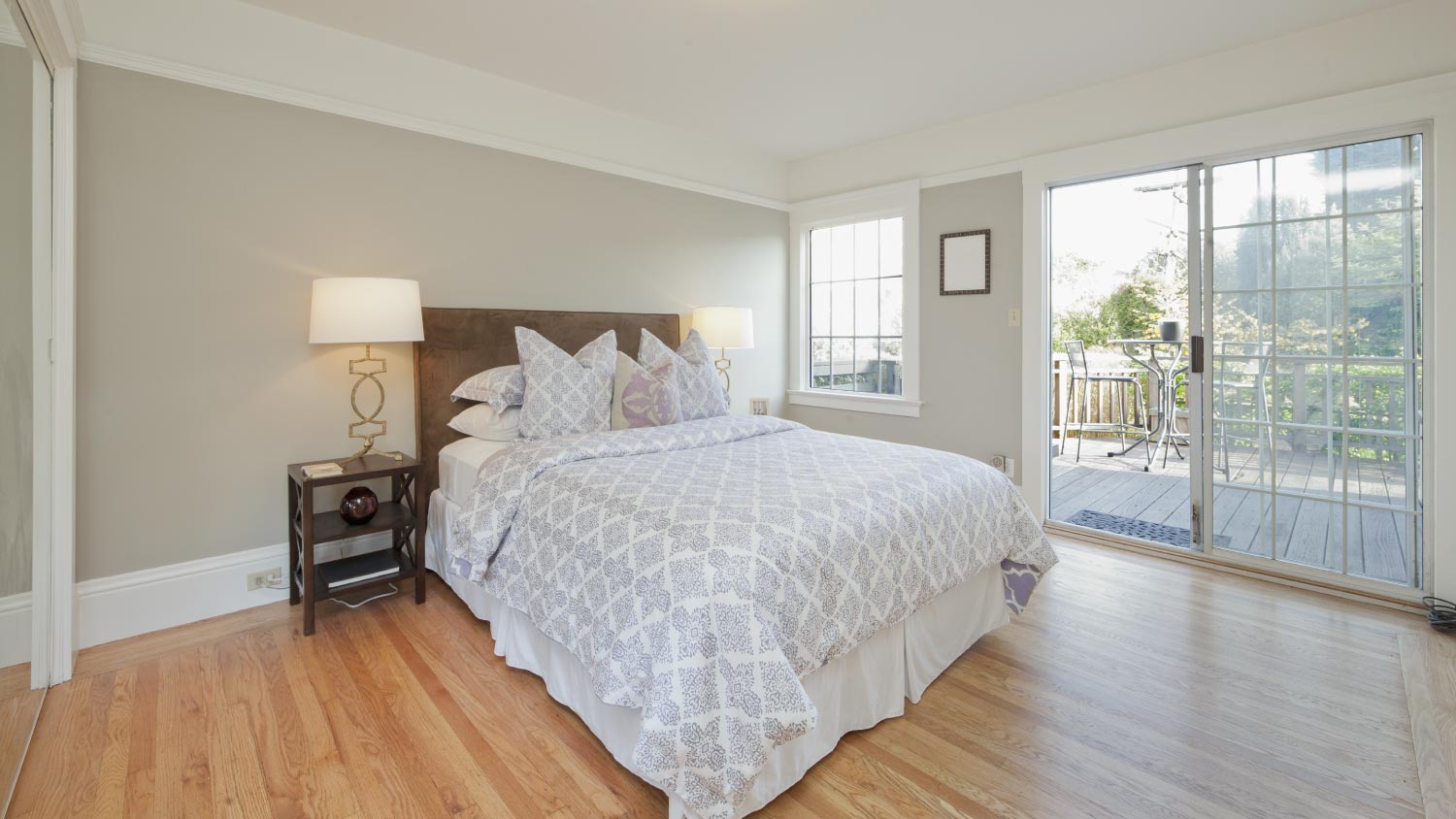 A bedroom with wooden floor and sliding glass door