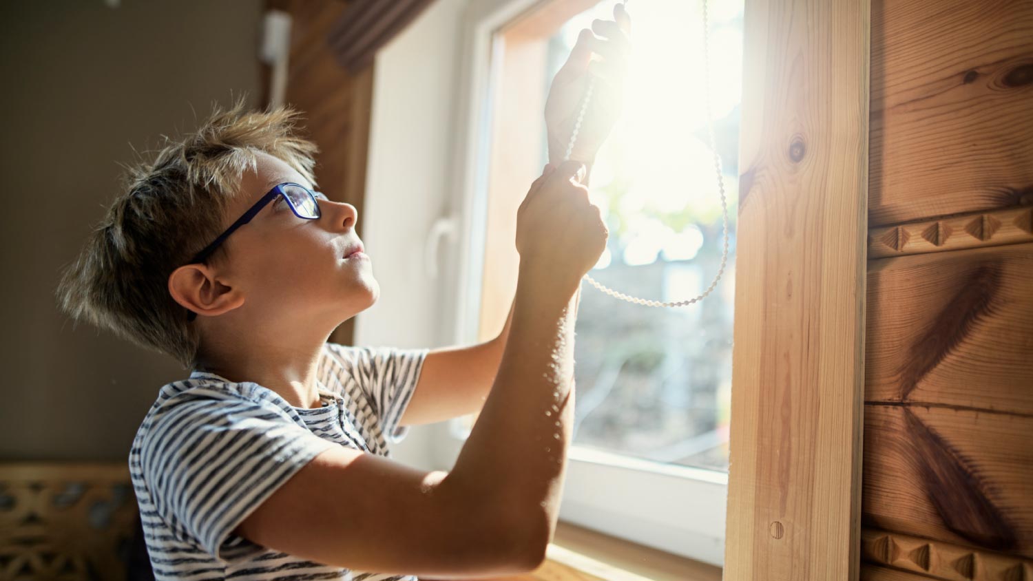 A boy closing the roller blinds