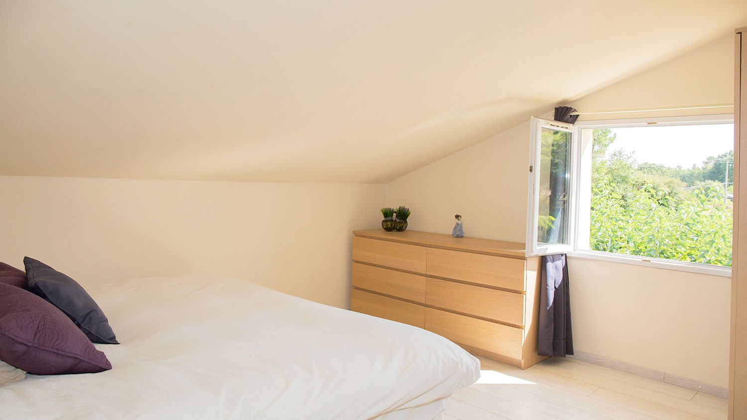 Bright low ceiling attic bedroom with a window