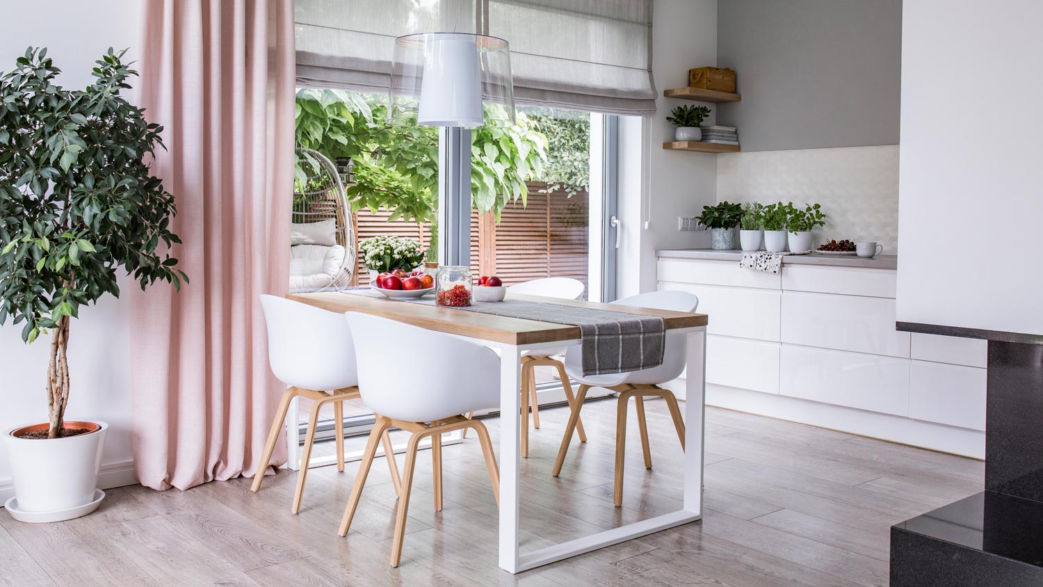 A bright kitchen with a dining table and a gray wall