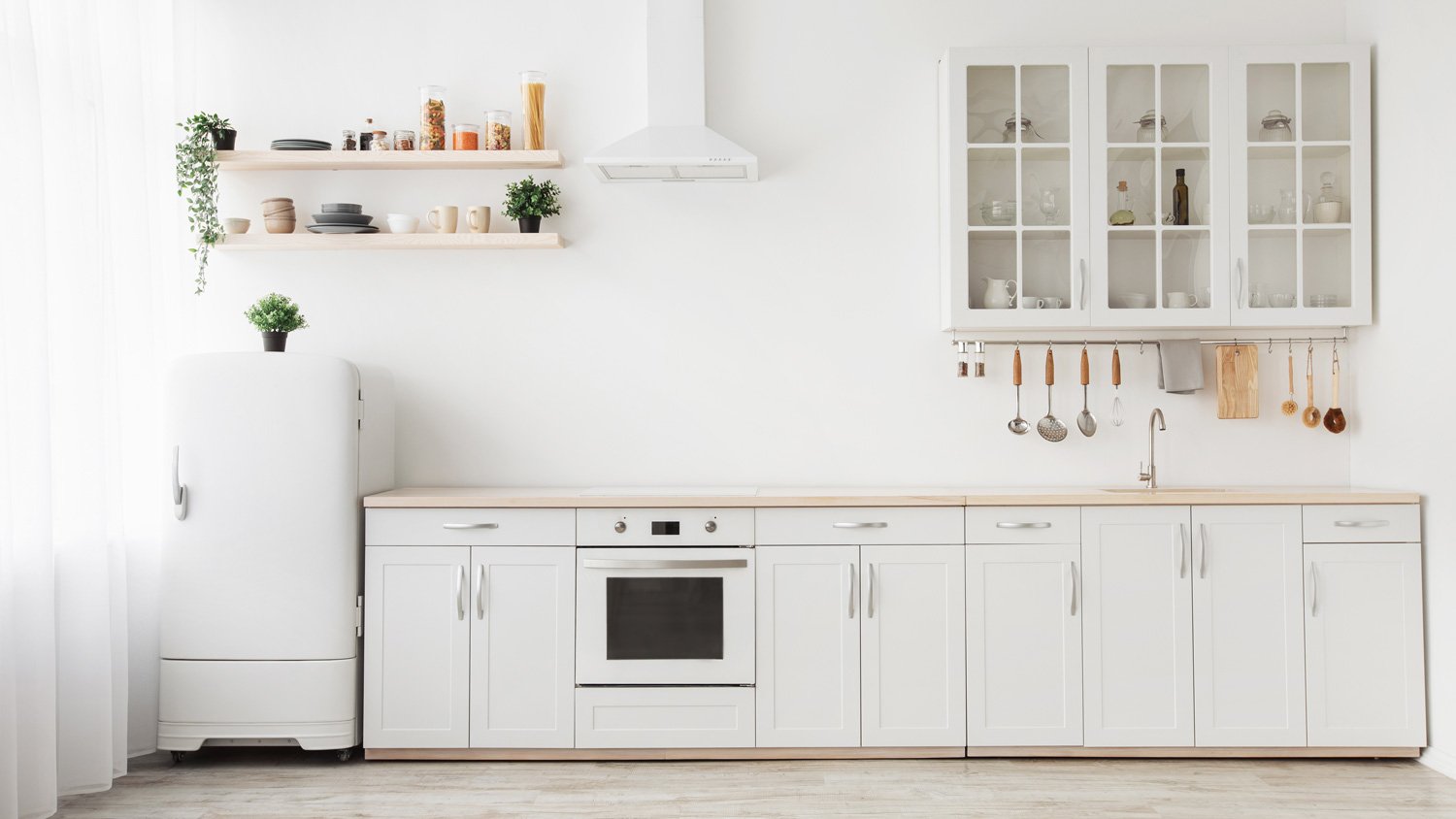 A bright minimalistic kitchen with white cabinets and appliances