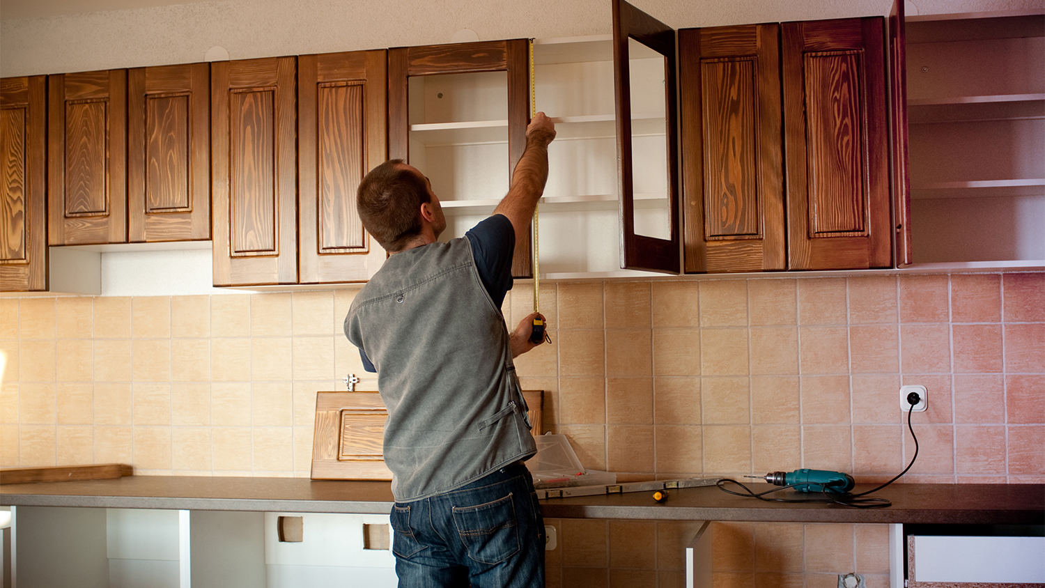 carpenter working on wood cabinets in new home       