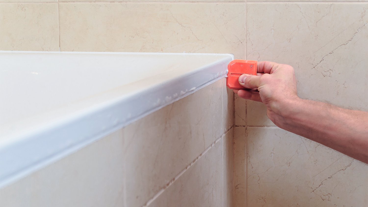 man uses tool to seal caulking