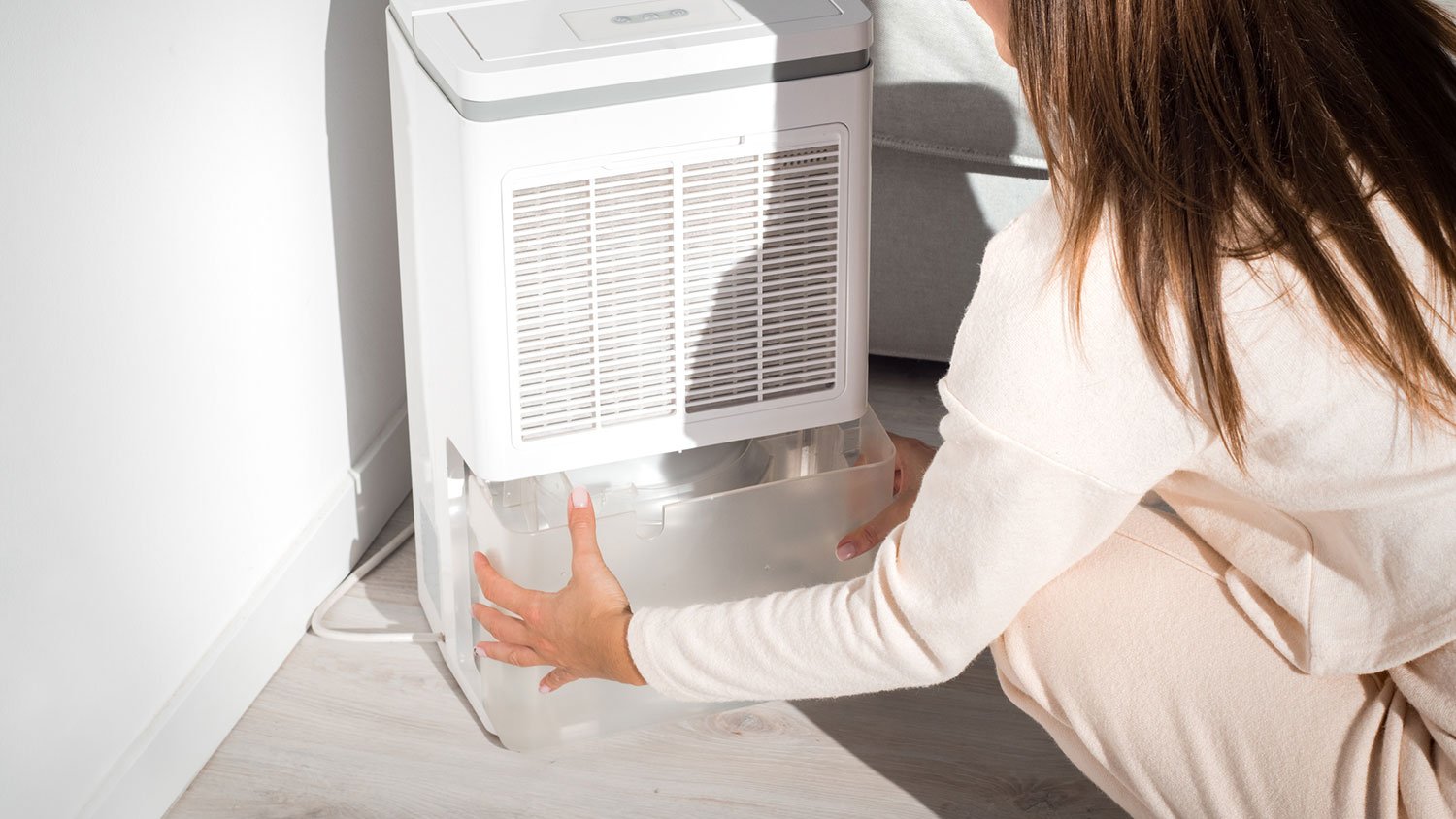 Woman changing water container in dehumidifier