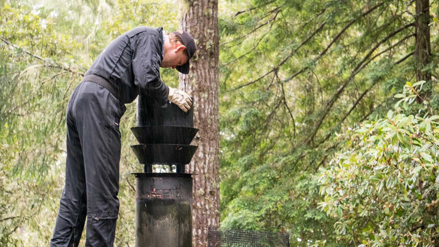 Worker on a house roof cleaning chimney