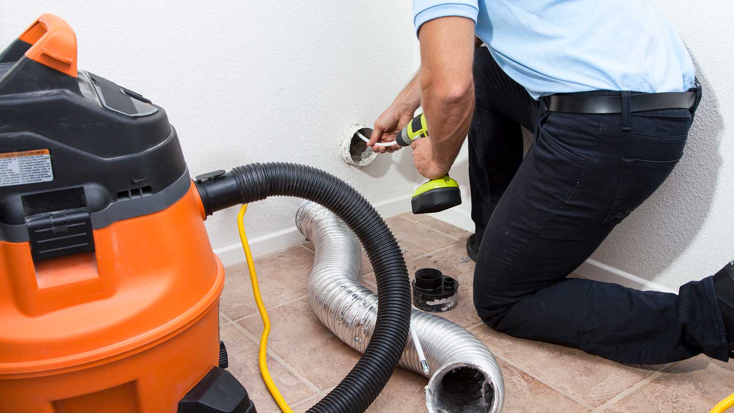 Worker cleaning dryer vent at home
