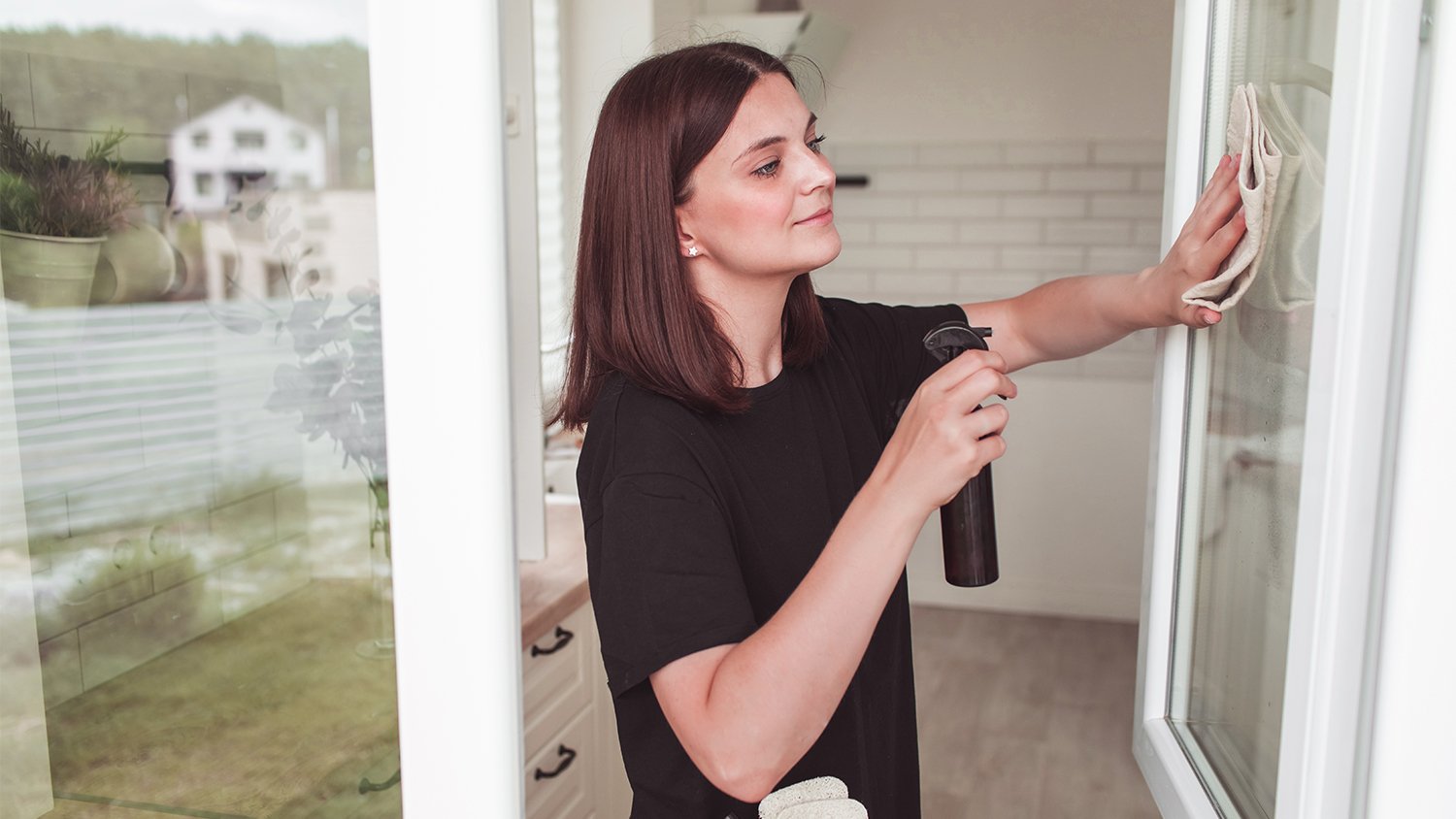 woman cleaning her windows with homemade cleaner