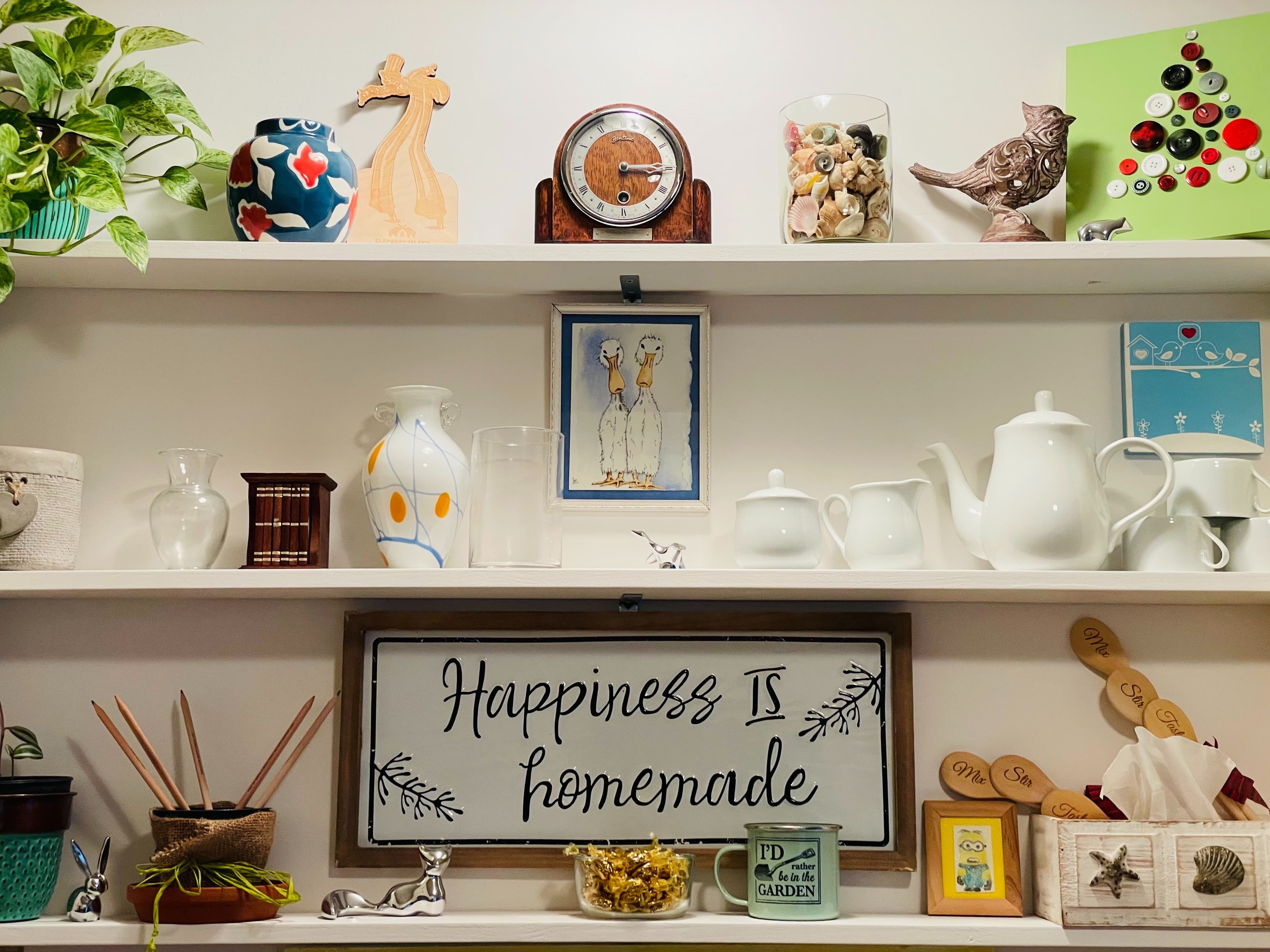 Kitchen shelves stacked with plants, candies, a clock, vases, and a tea set