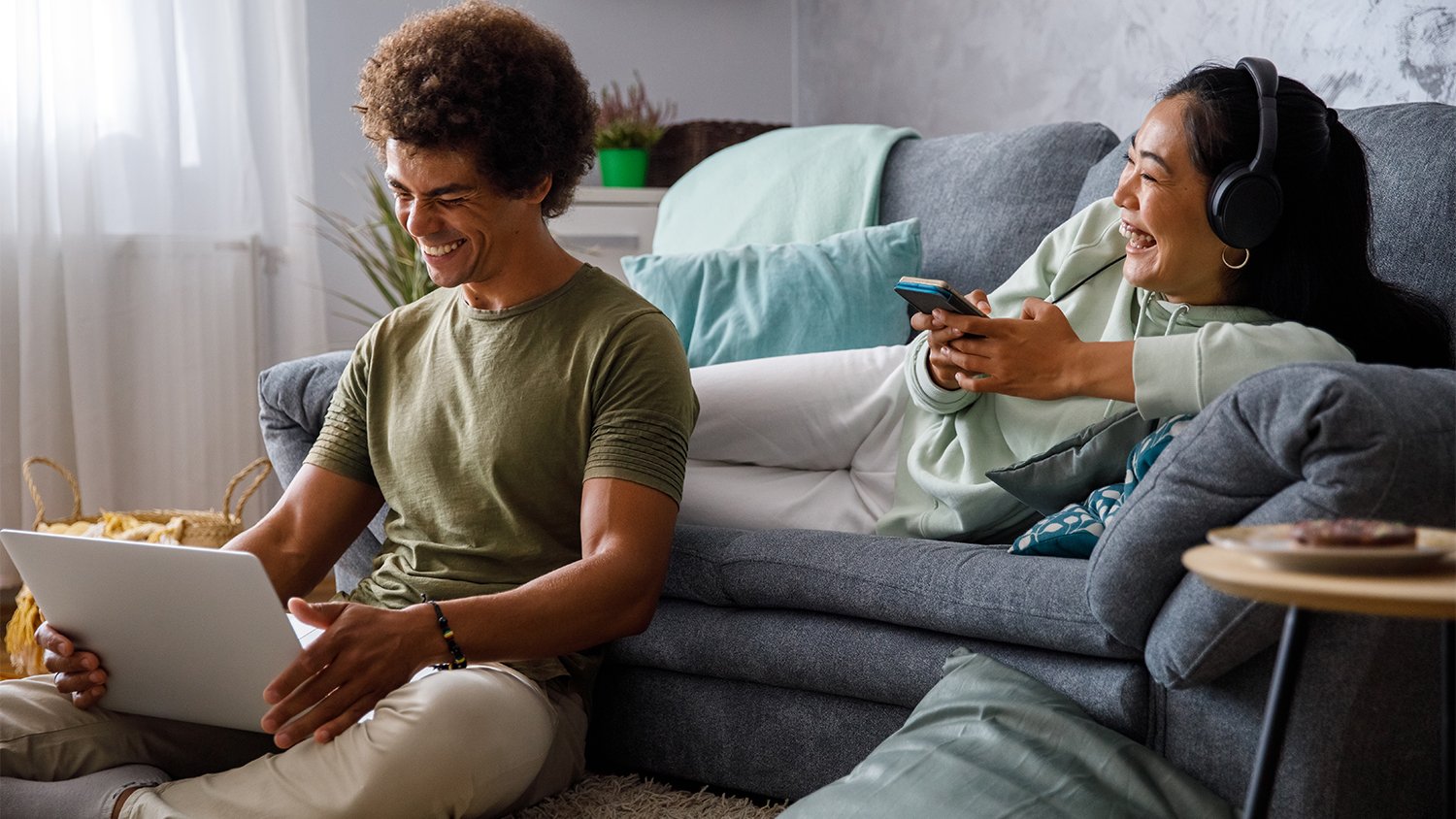 couple hanging out in the living room while on the phone and computer 