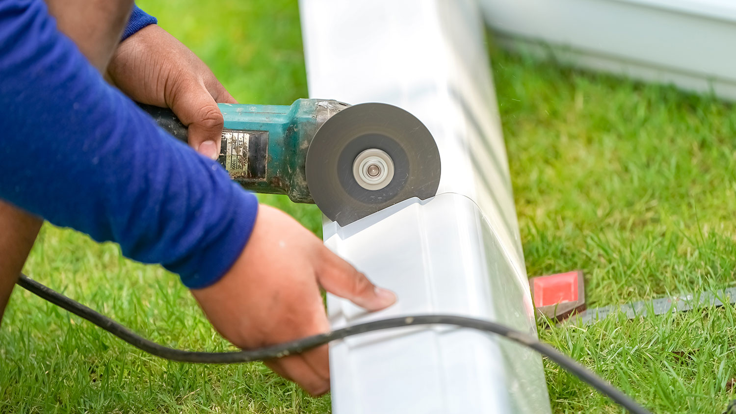 Worker cutting gutter with electric saw