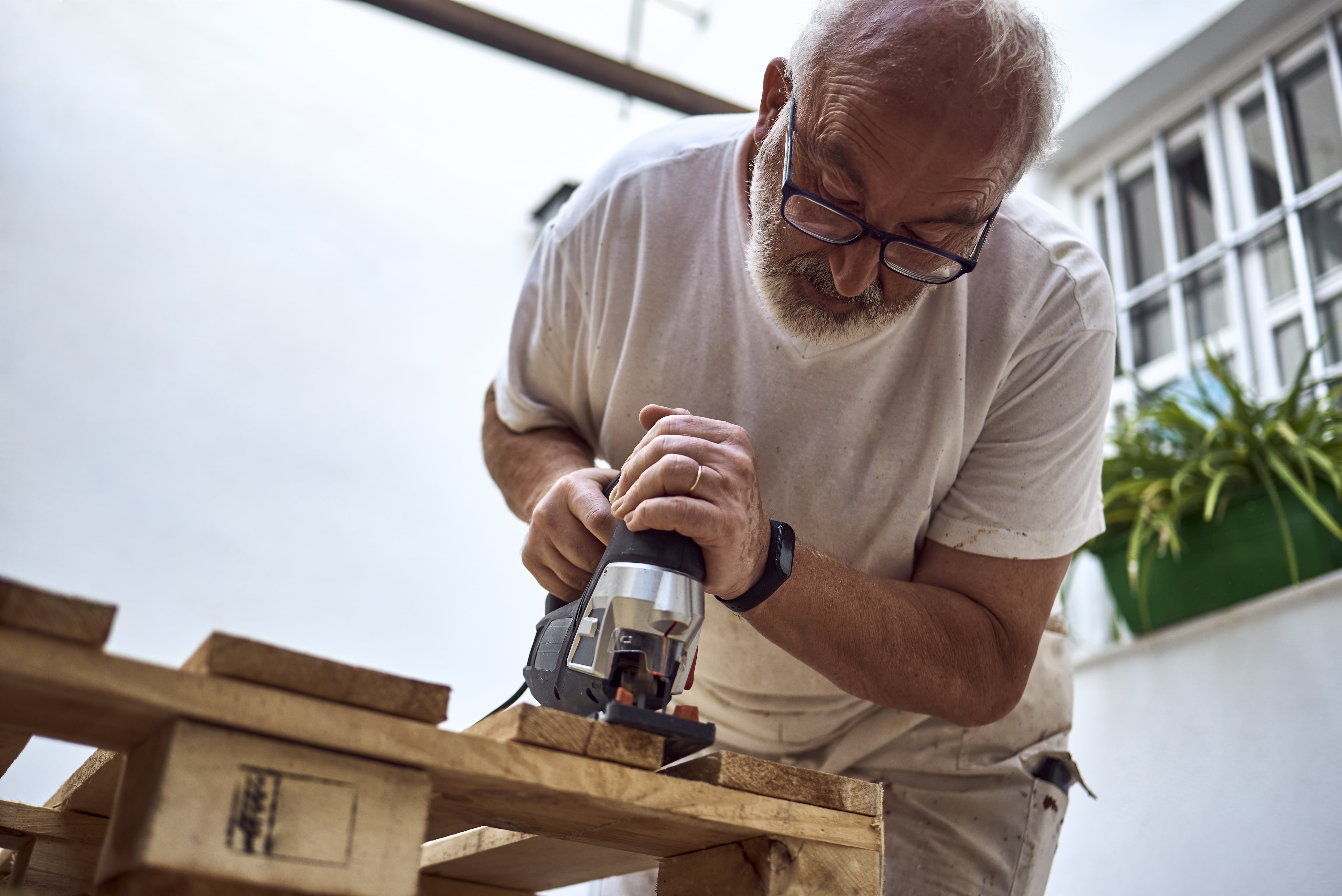 Man deconstructing pallet using a jigsaw