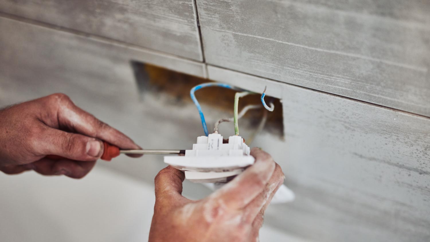 An electrician fixing wires in the wall