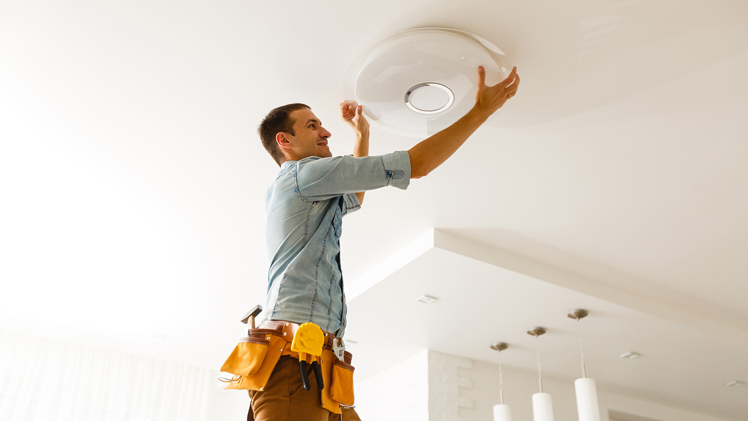 Electrician installing new ceiling lamp