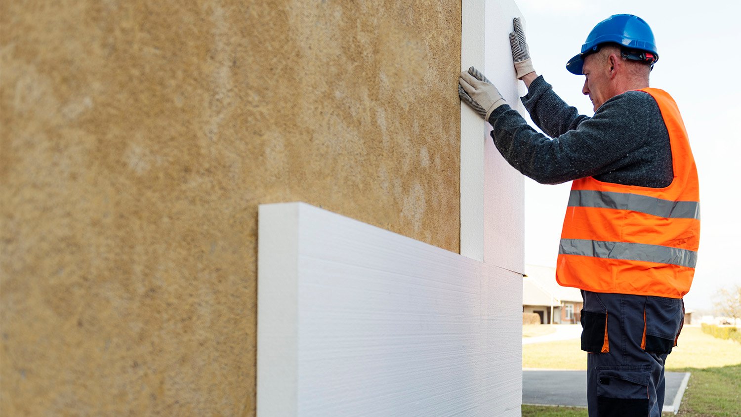 construction worker putting foam insulation on exterior of home