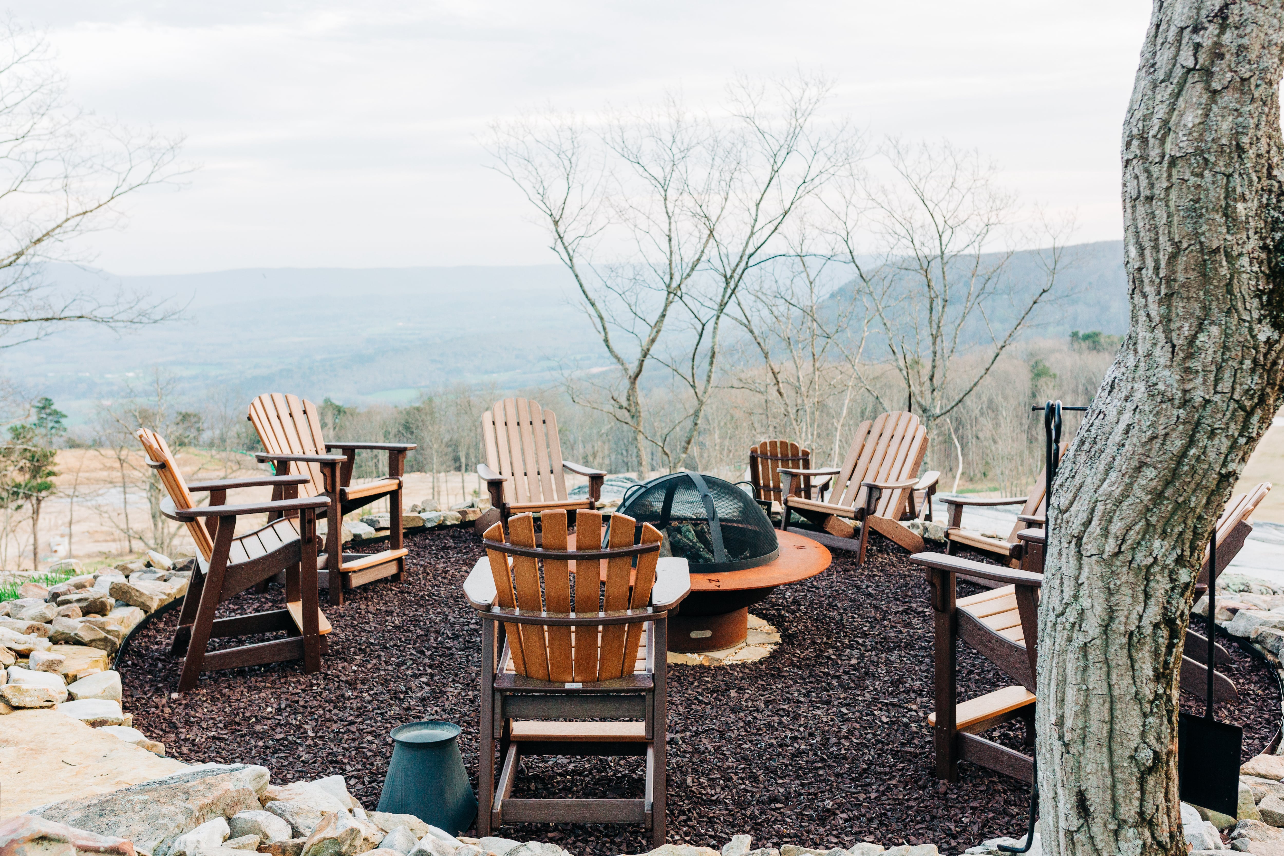 A designated fire pit area with a metal fire pit and Adirondack chairs on loose gravel