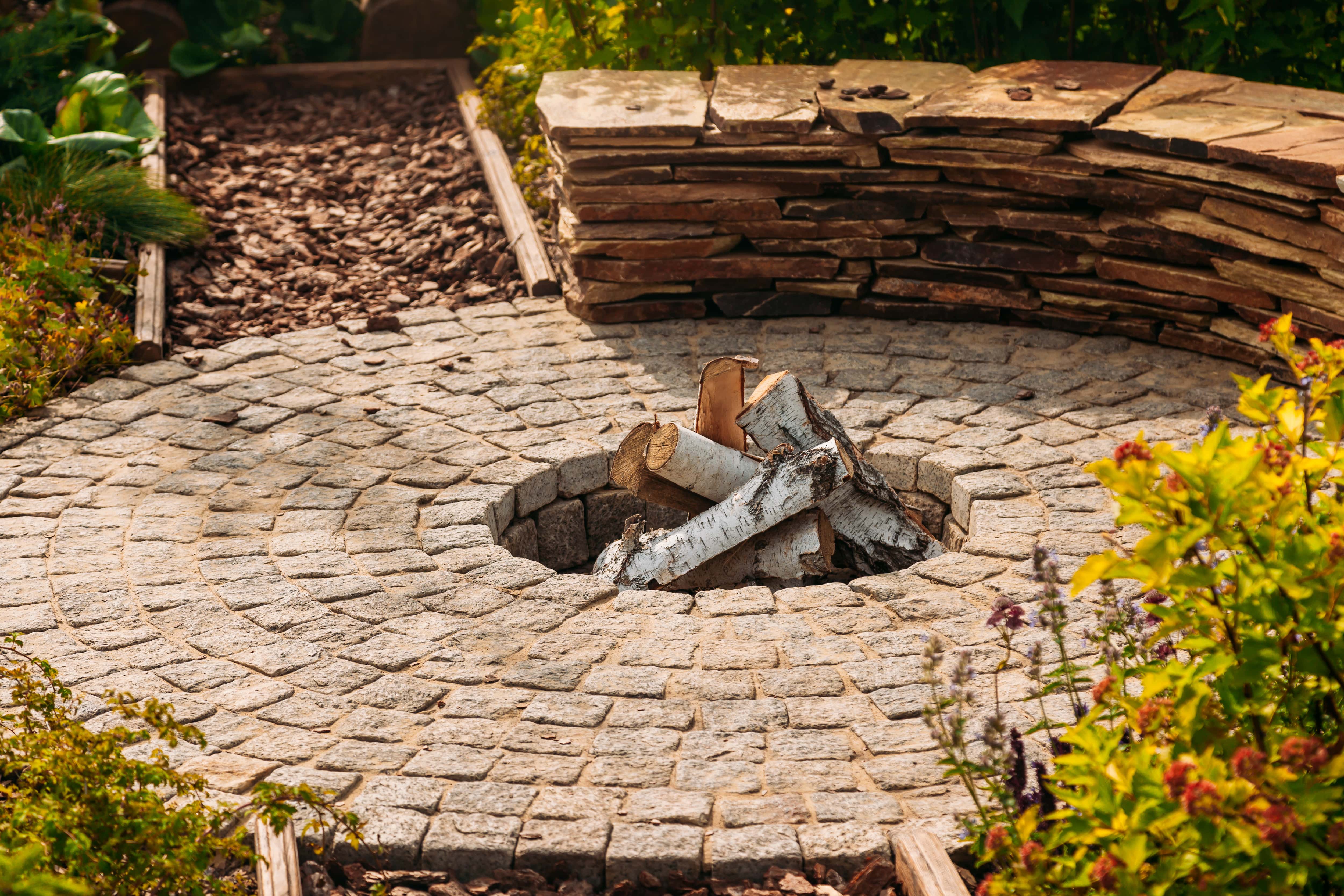 An in-ground fire pit surrounded by a brick platform and stone slab benches