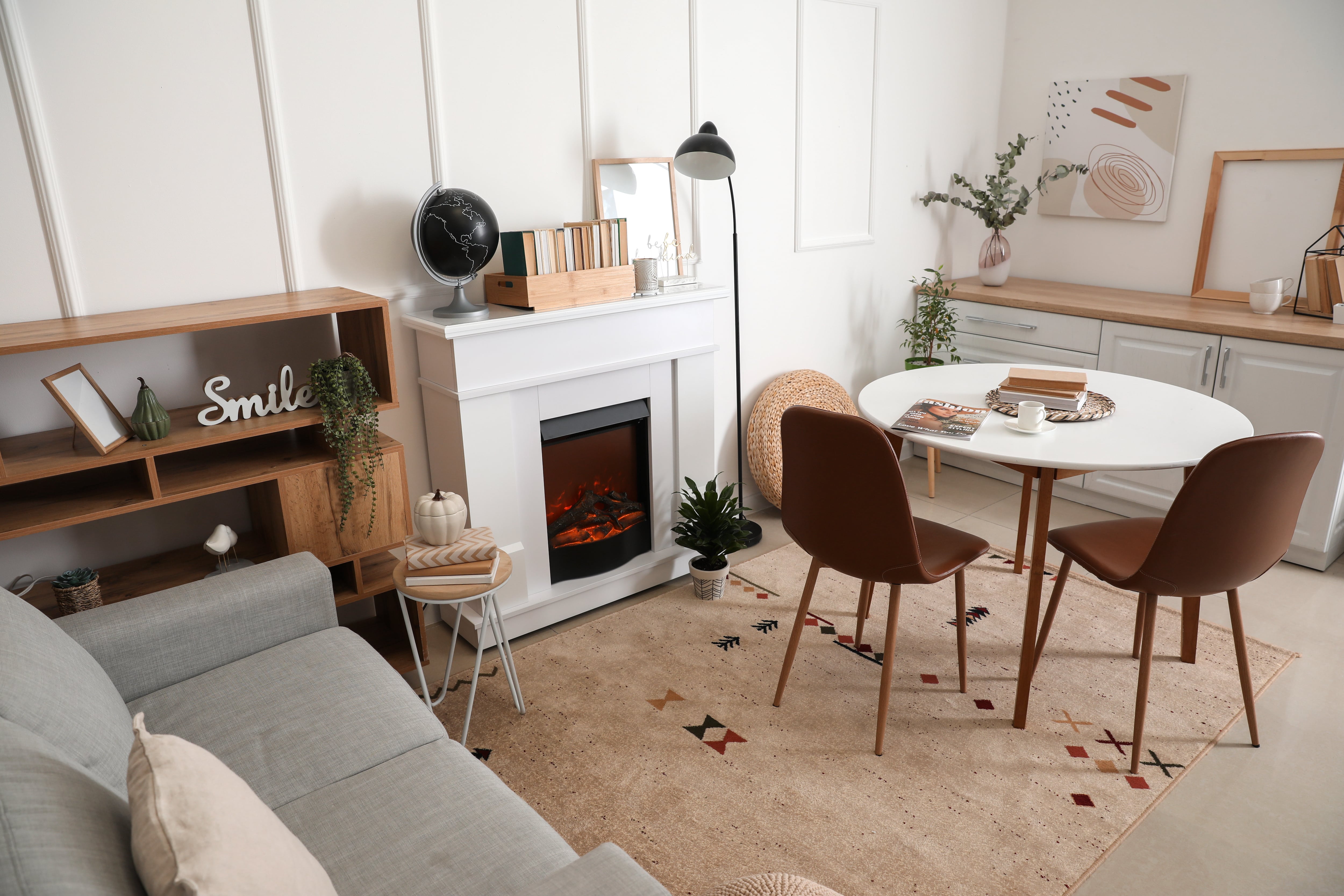 Fireplace decorated with books next to a table and a couch 