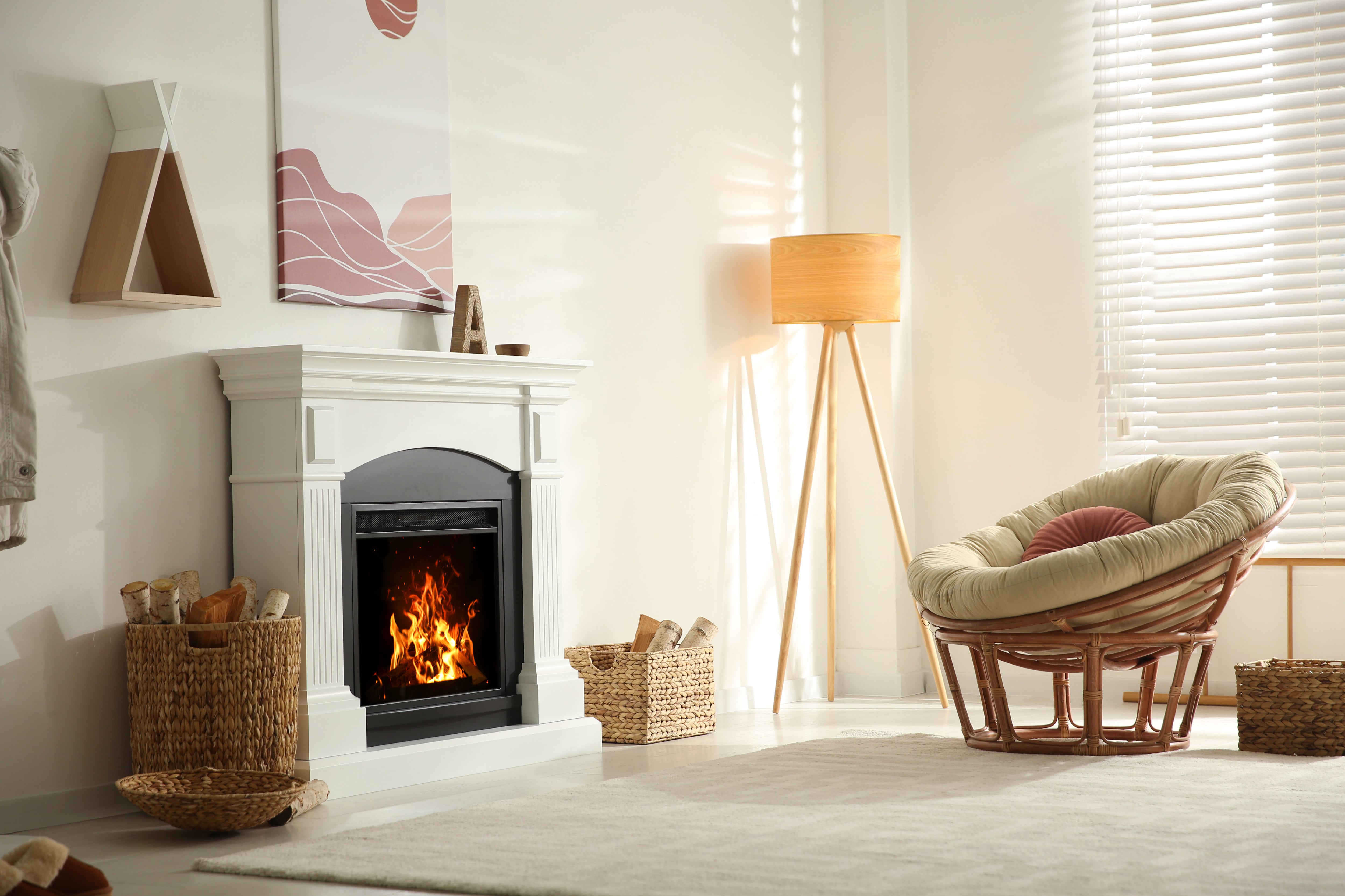 White fireplace with pink abstract painting on wall above it and papasan chair