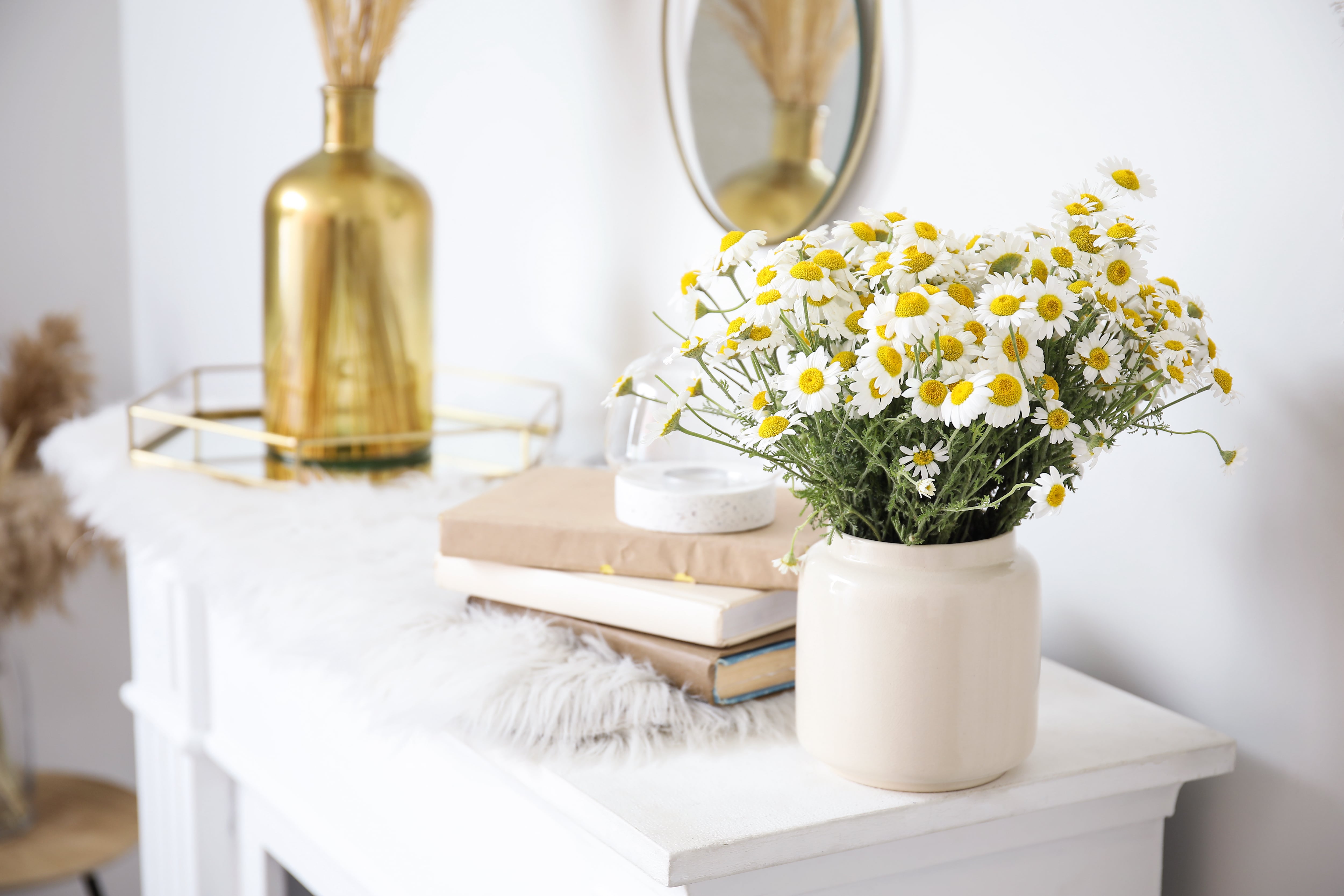 Fireplace mantel decorated with flowers, vase, and books
