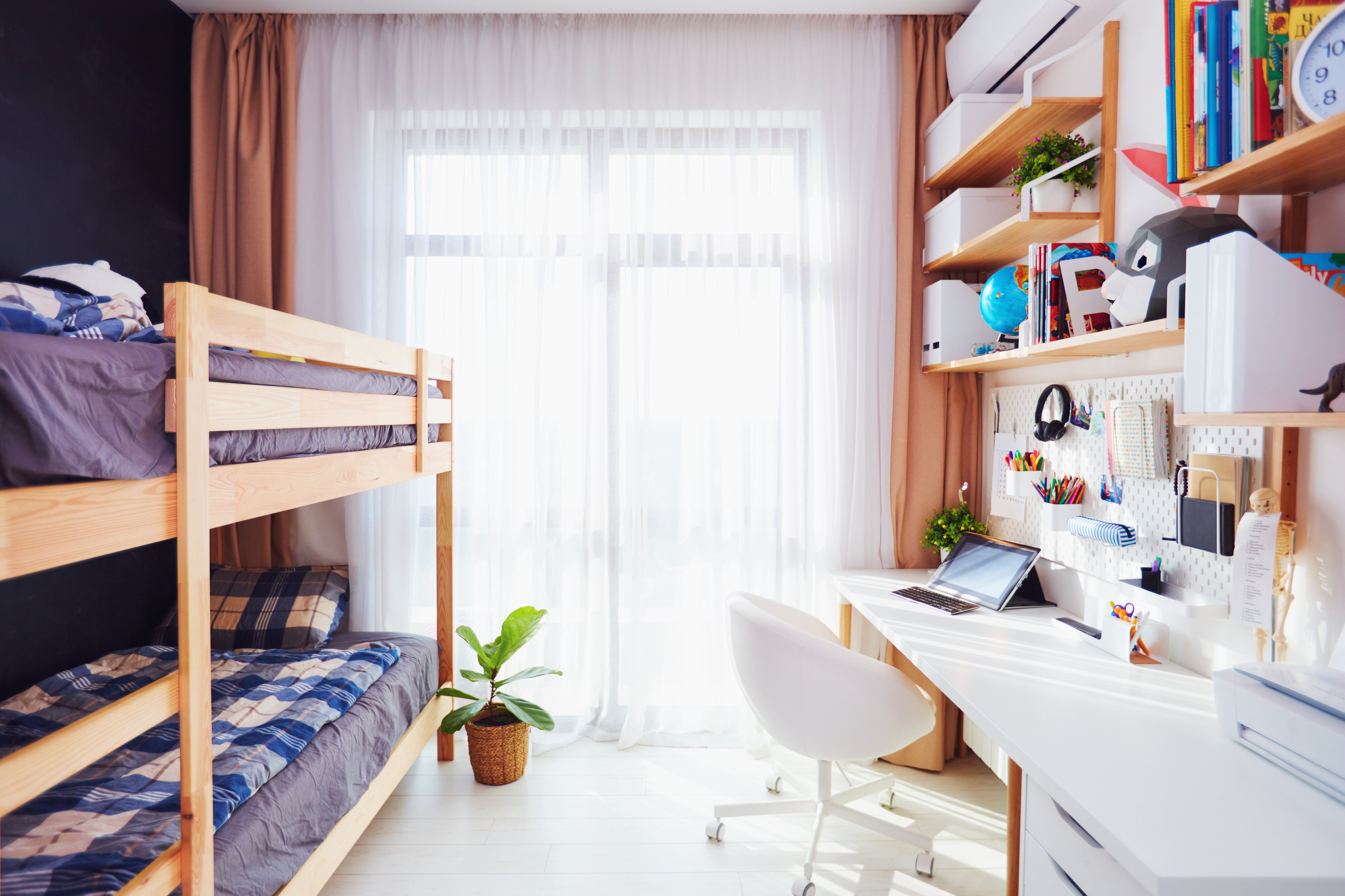 A stylish kids bedroom with a bunk bed, a desk, and floating shelves