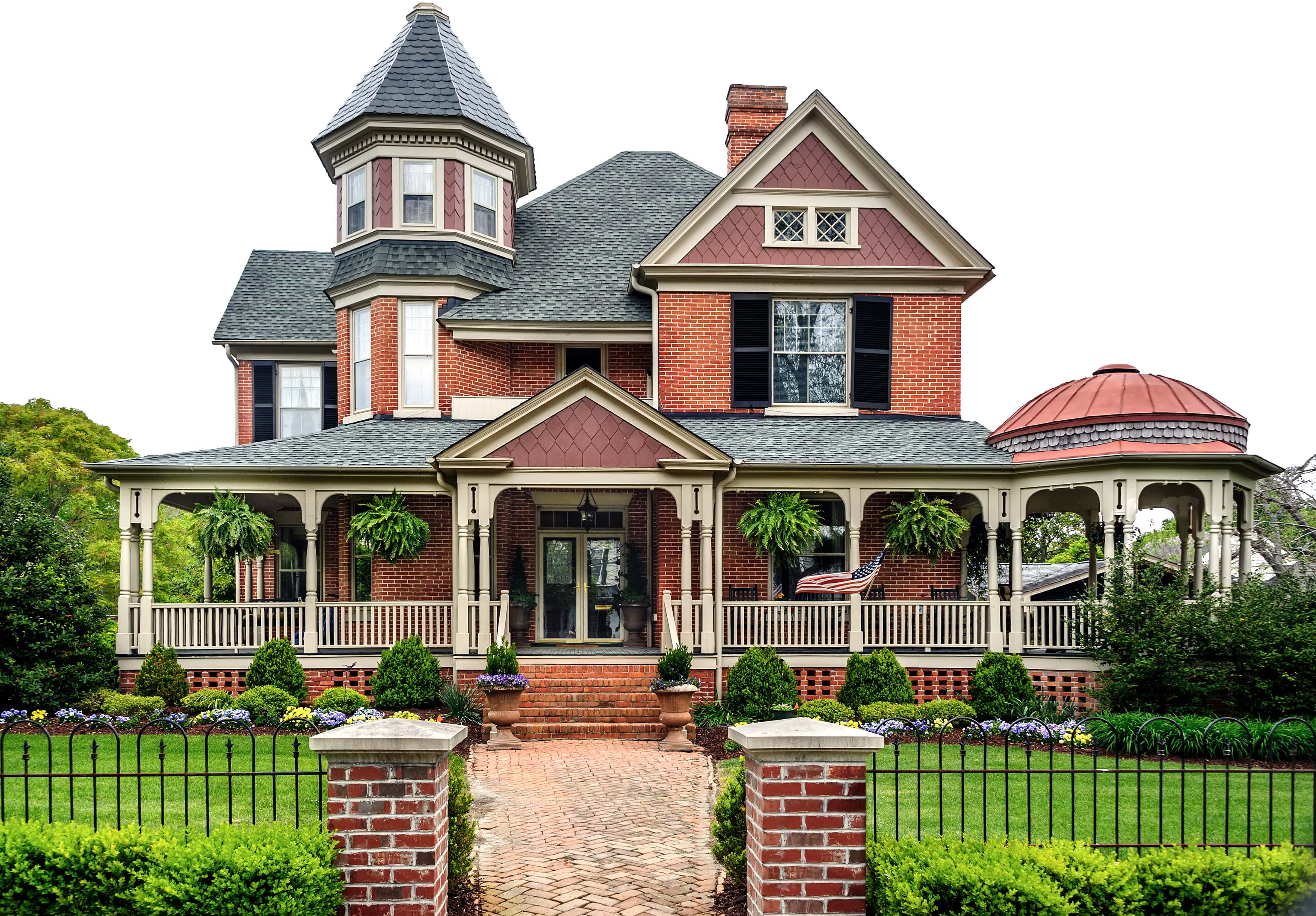 Brick Victorian house with a black fence in the front yard