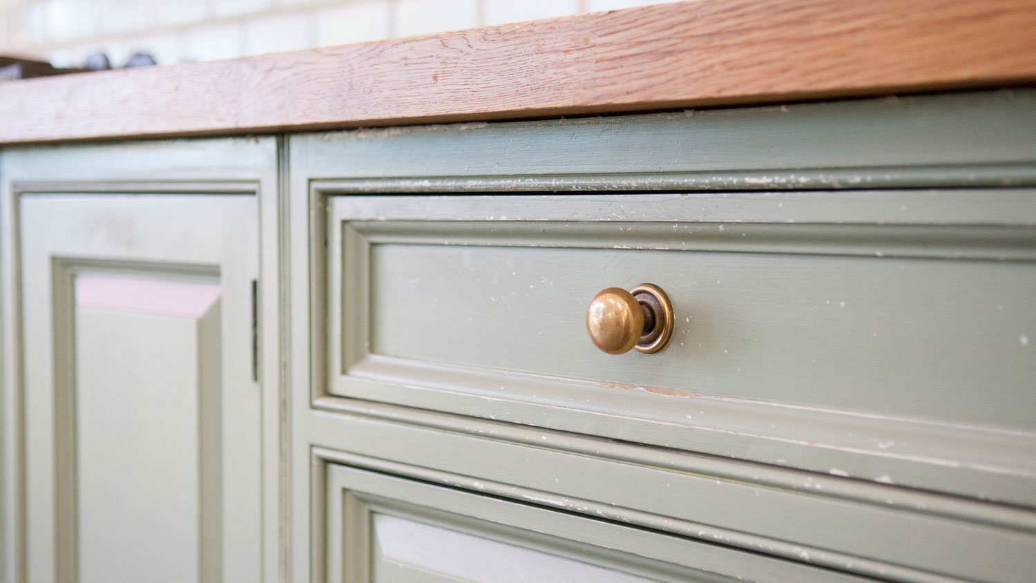 A green kitchen cabinetry with a brass knob