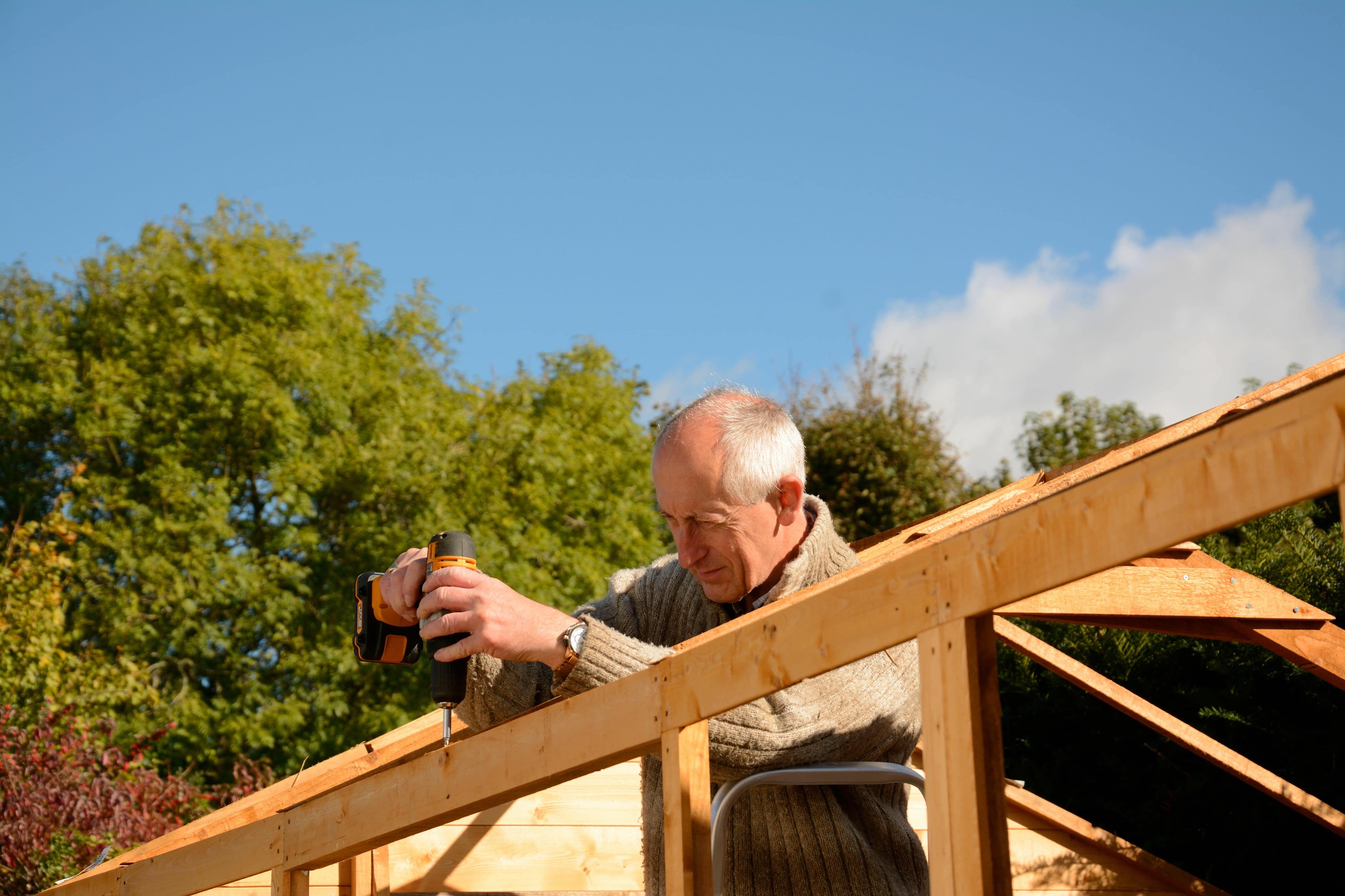 A man installing a roof frame with an electric drill