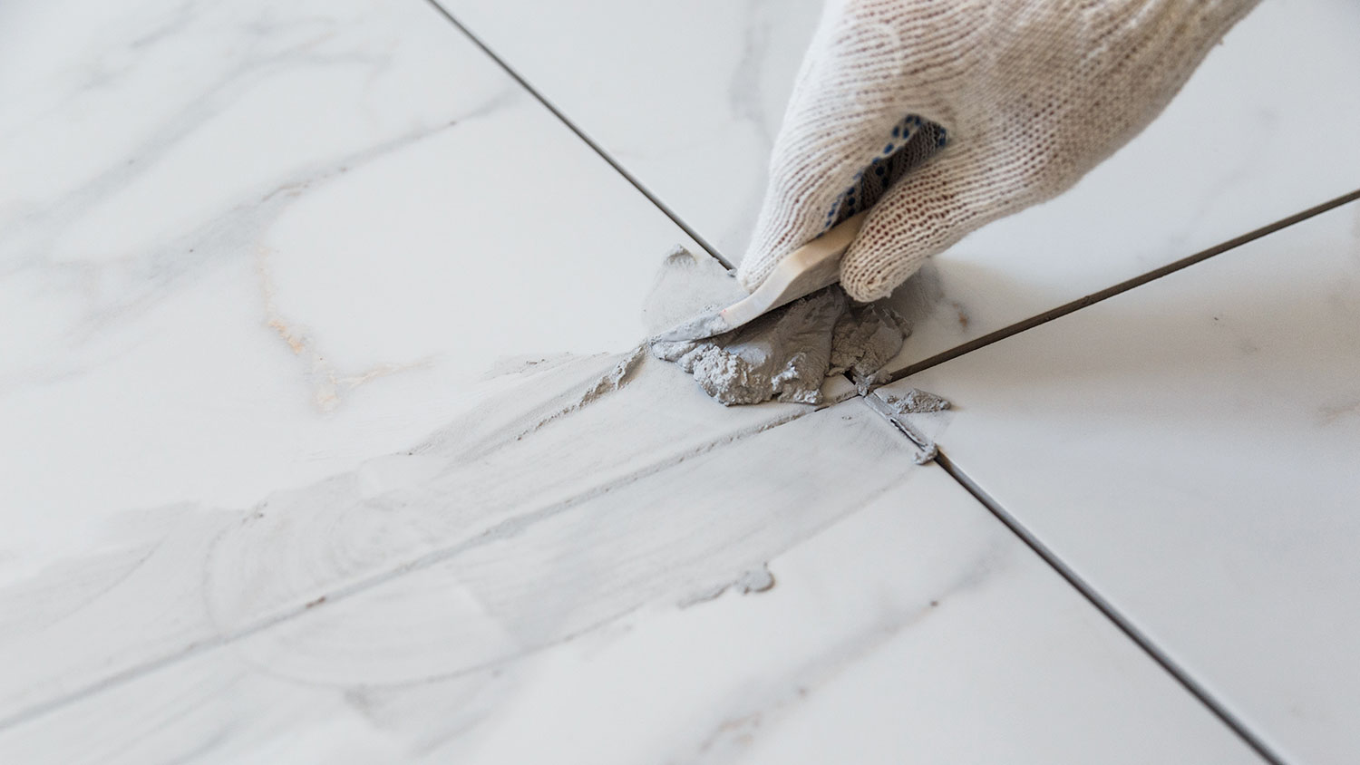 Closeup of a hand grouting tile