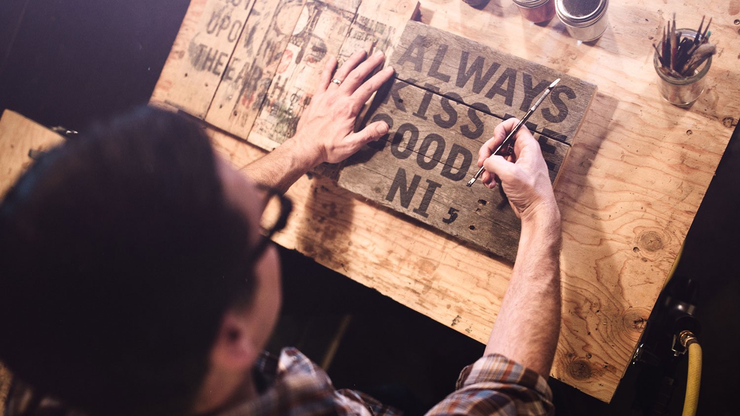 Artist painting wooden sign in his studio