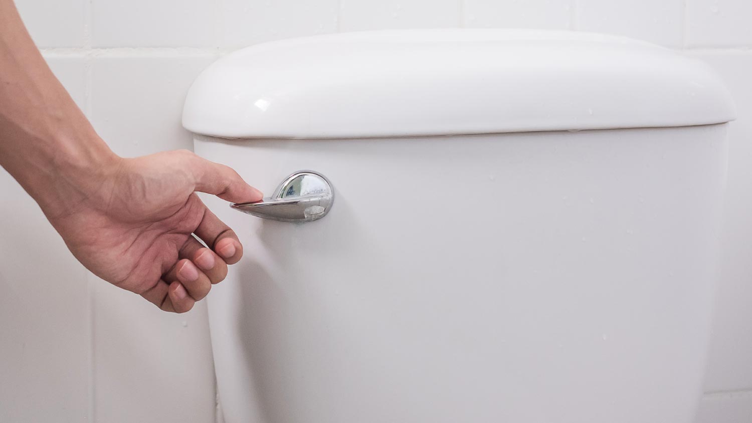 A hand flushing a toilet